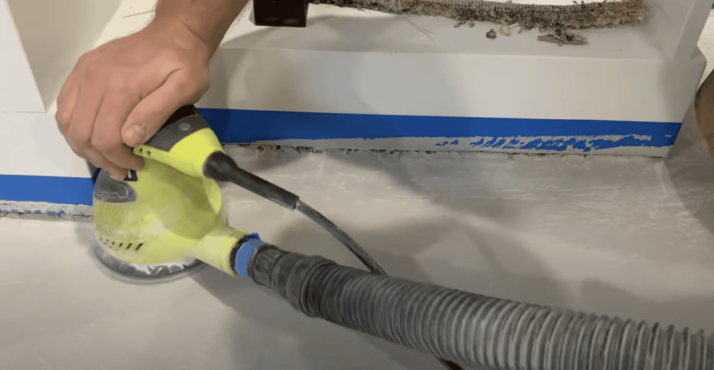 After our texture coat of concrete overlay is dry, we begin sanding the entire floor.  In this photo we are using a small palm sander.