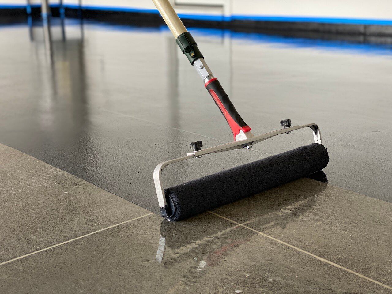 Black epoxy primer being applied to a floor with a roller.