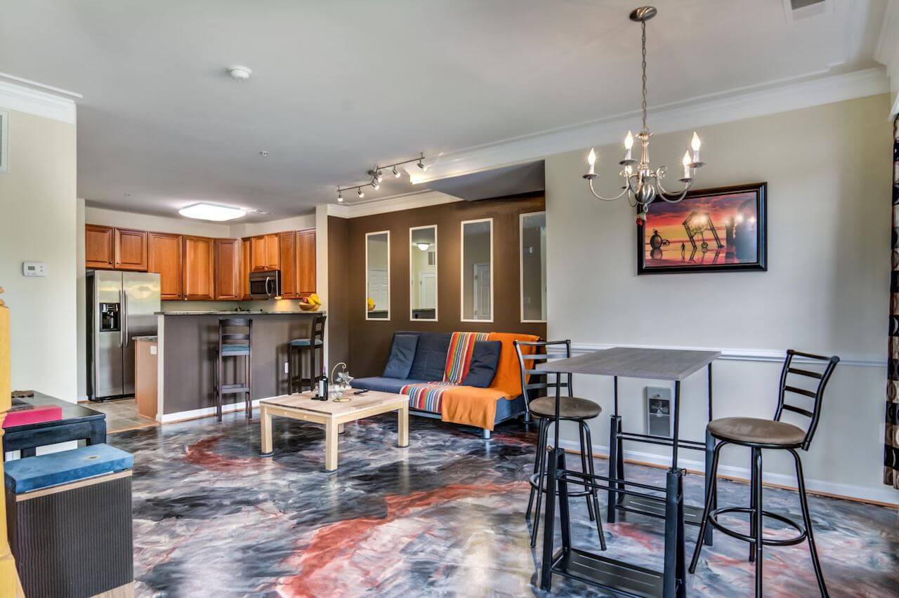 The main living area of an open concept home features Leggari epoxy floors in several colors including black, gray, red, and blue.