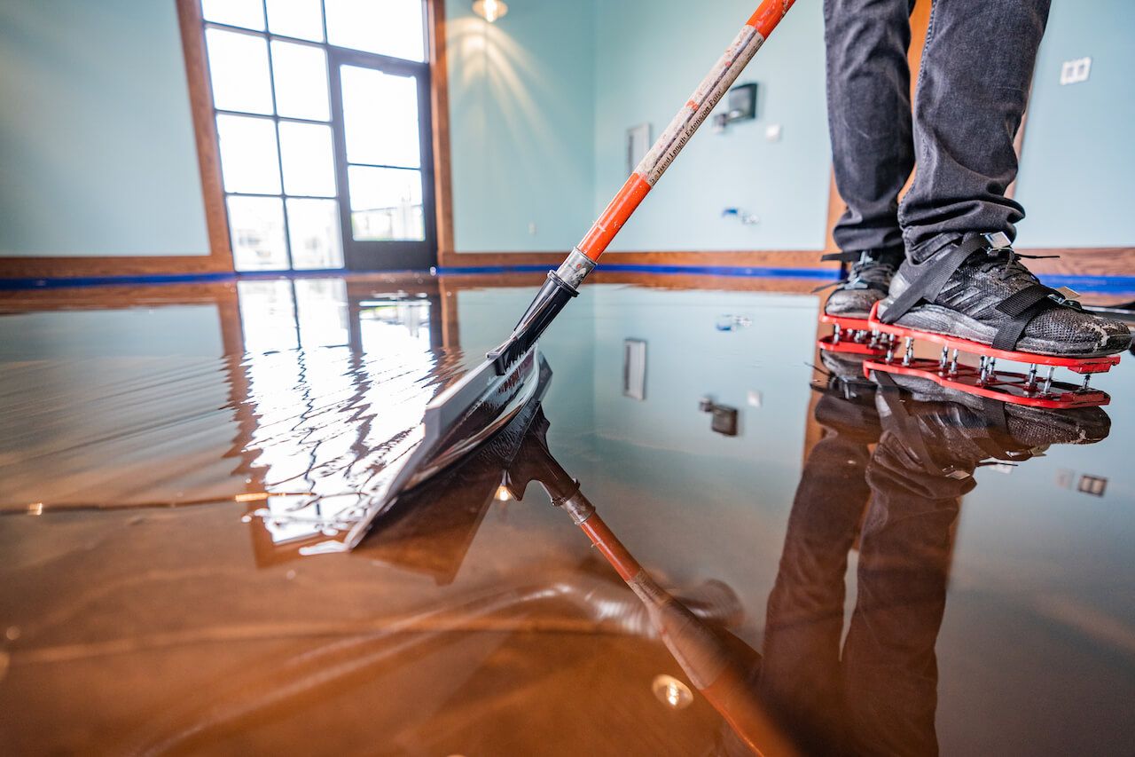 Applying a Leggari metallic epoxy floor using a Leggari squeegee while wearing Leggari spike shoes.