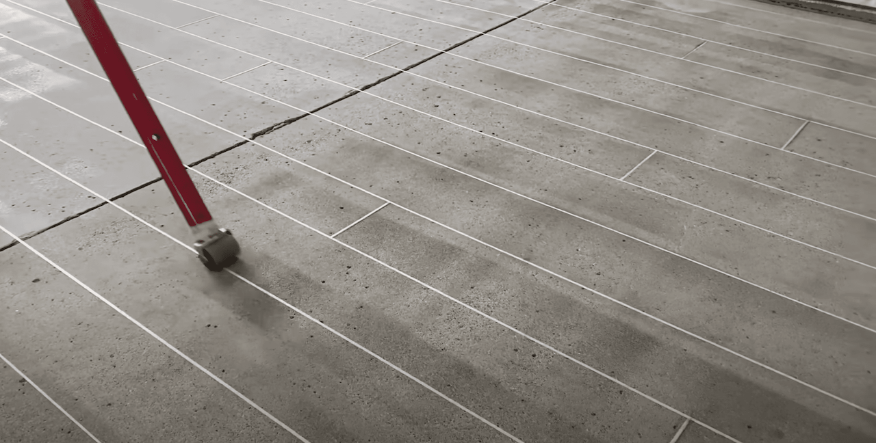 Creating the hardwood overlay pattern using a high-fiber filament tape and pressing it down with a specialize rolling wheel.