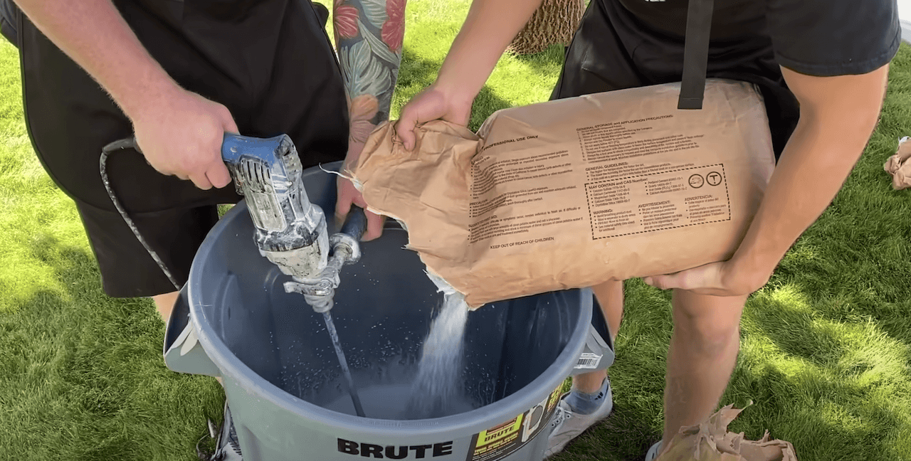 Mixing the liquid polymer with the dry concrete overlay mix using a paddle wheel attached to an electric drill.